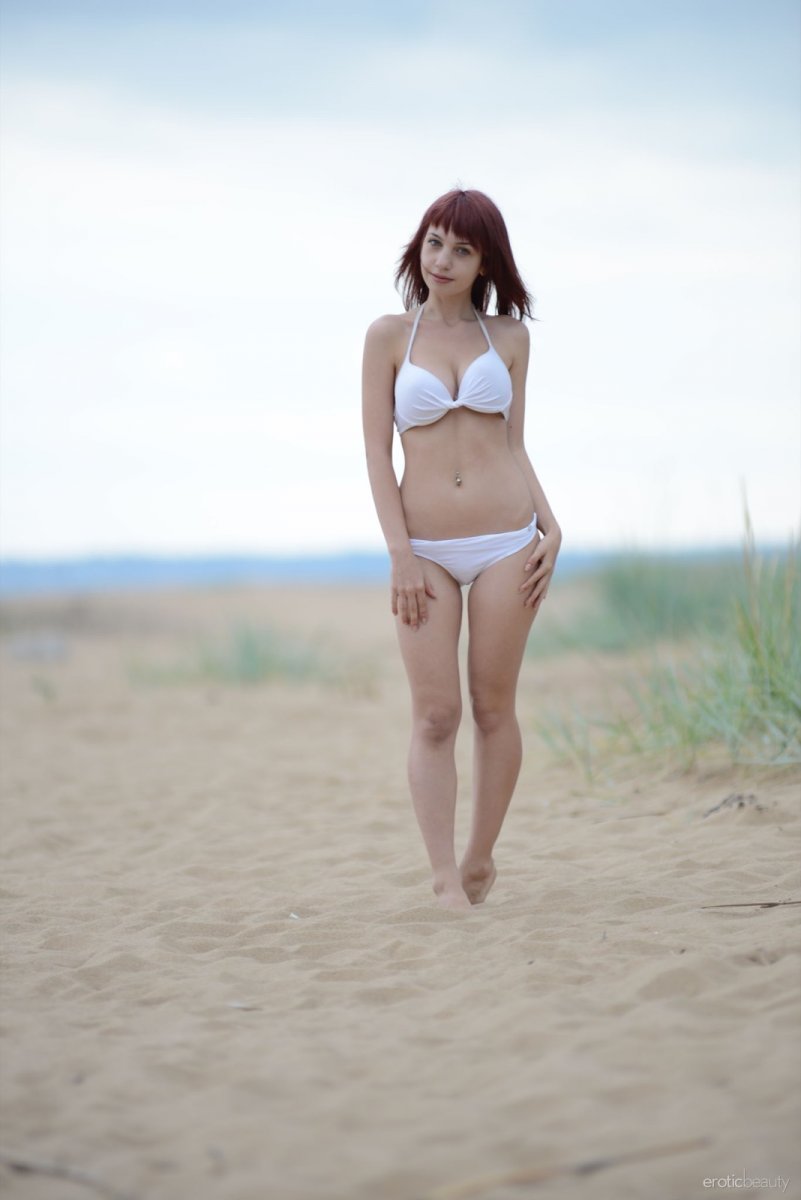 A titty chick in a white swimsuit undressed on the beach
